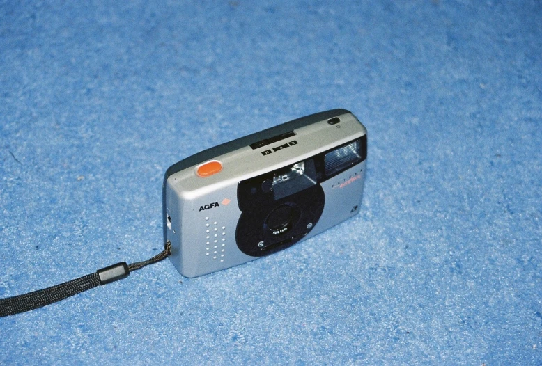 a camera sitting on a blue surface with an orange flash light attached