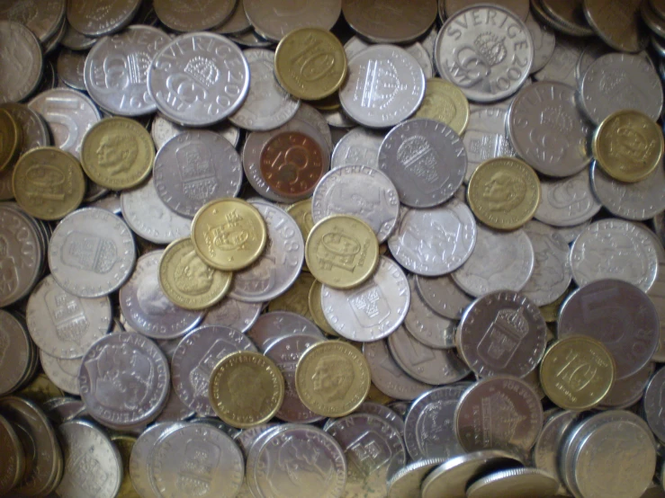 a pile of silver and gold coins with the canadian coat on top