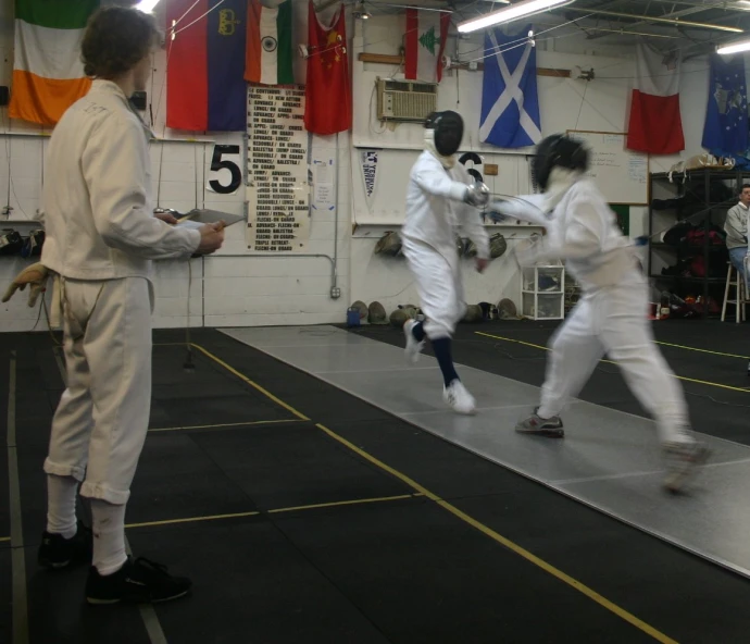 people in kimonos practicing karate moves at the gymnasium