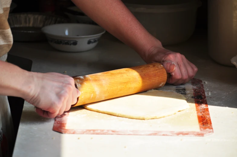 a person  and rolling dough on a large wooden spoon