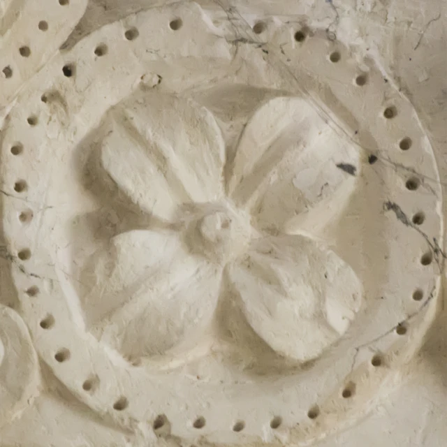 the carved wall is holding several flowers