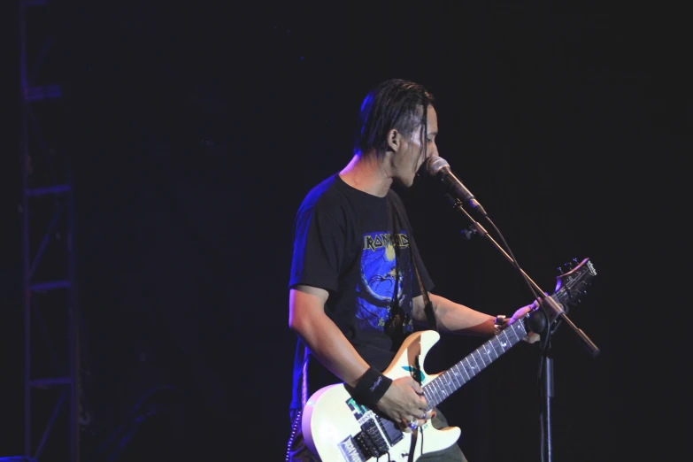 a man with a guitar sings into the microphone