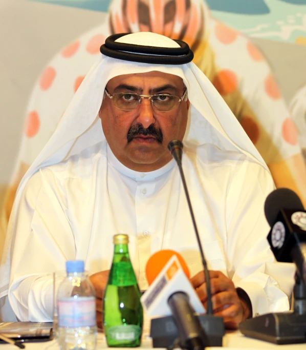 a man wearing glasses sitting in front of microphones and bottles