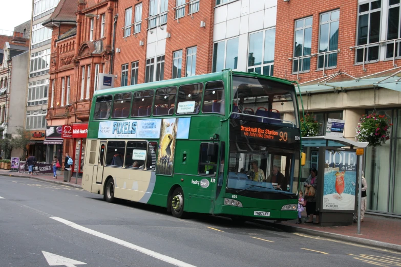 the two story green bus is driving down the street