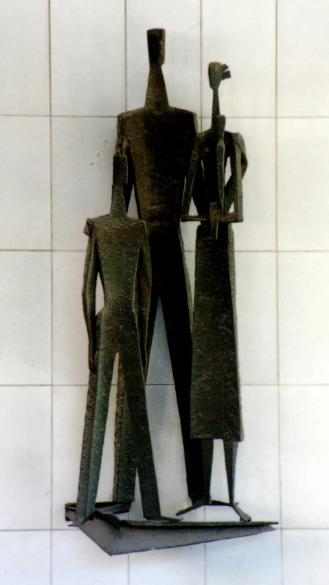 three statues in silhouette standing against a white tiled wall
