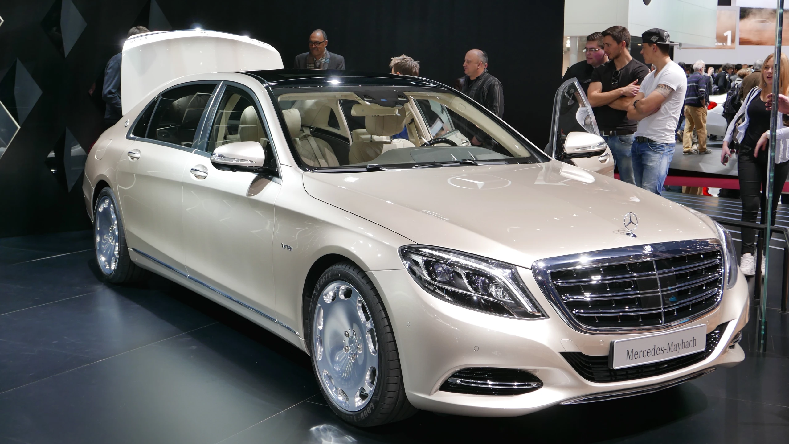 people looking at luxury vehicles displayed on floor