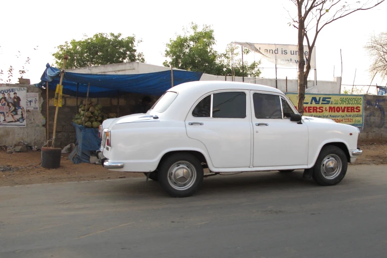 an old white car on the street near tents