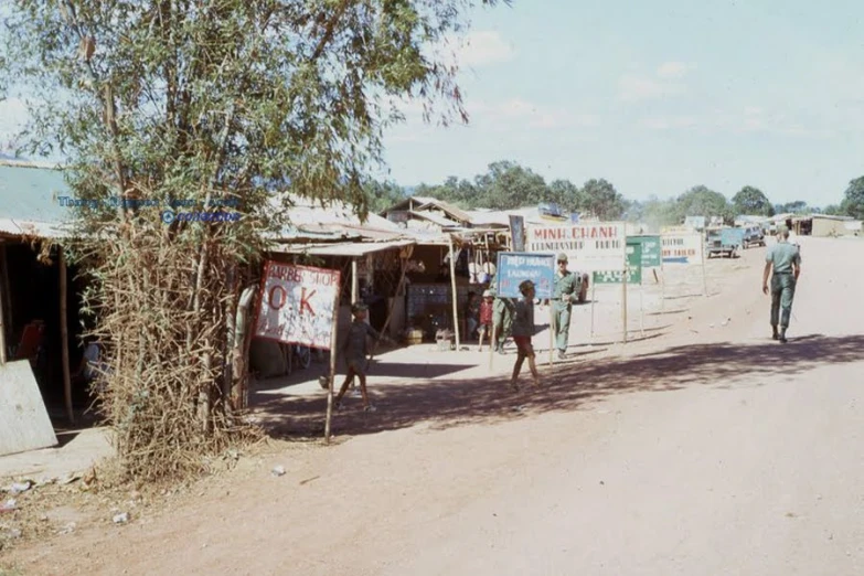 three people walking down the street in a village