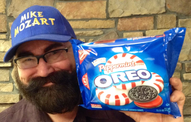 a man wearing a blue hat is holding a bag of oreo marshmallows