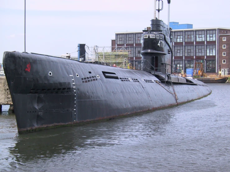 a submarine sits at the dock near some buildings