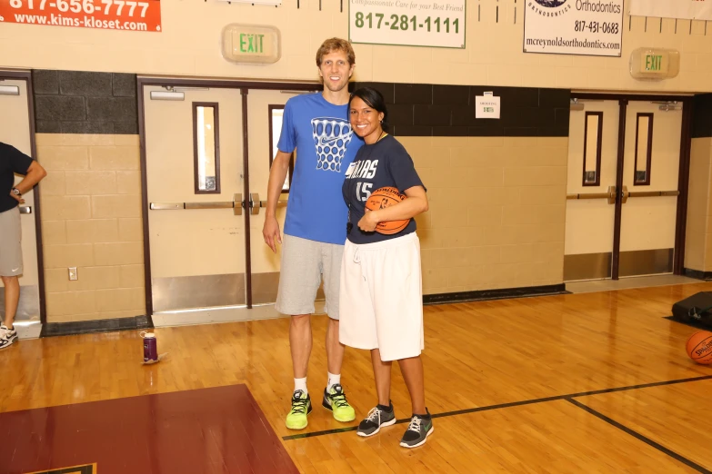 a young man and woman standing in a gym posing for the camera