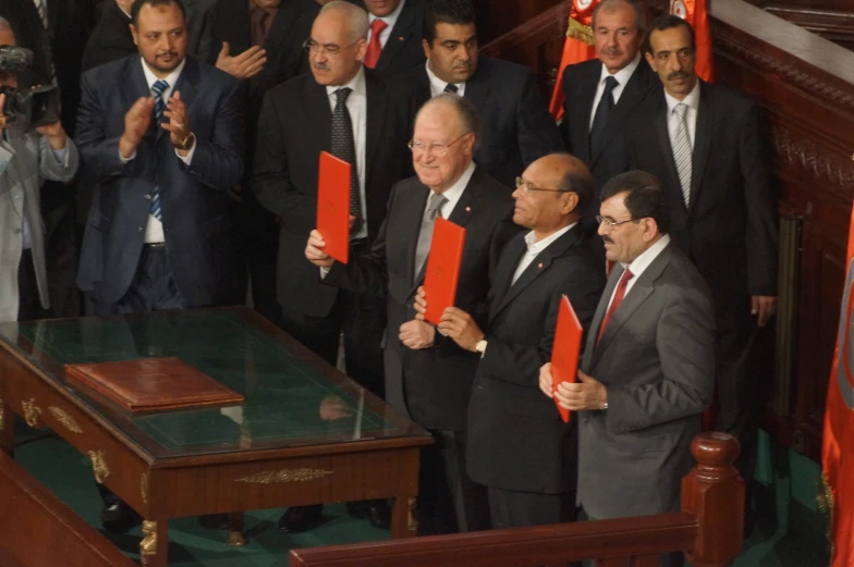 two men are standing in front of two other men holding red items