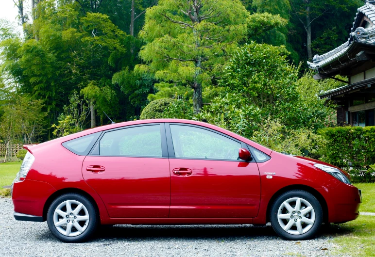 a red car parked on the gravel by a building