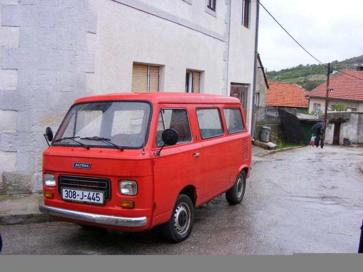 an old red van parked on a wet street