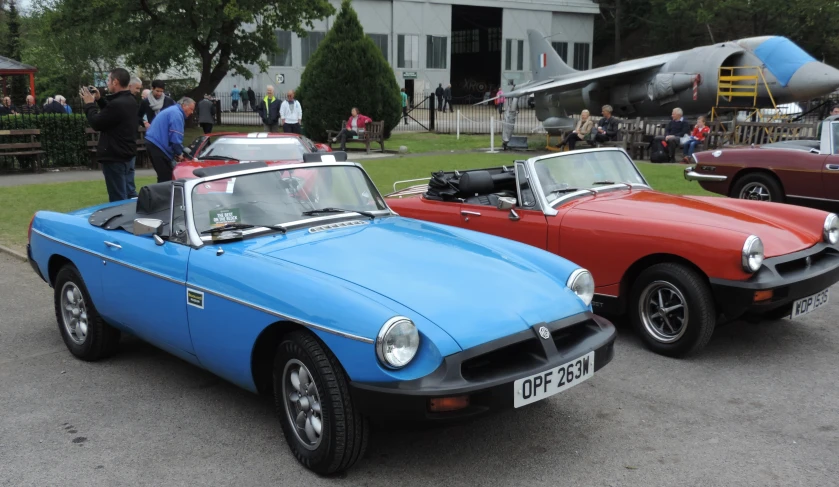 two classic cars parked side by side in a parking lot