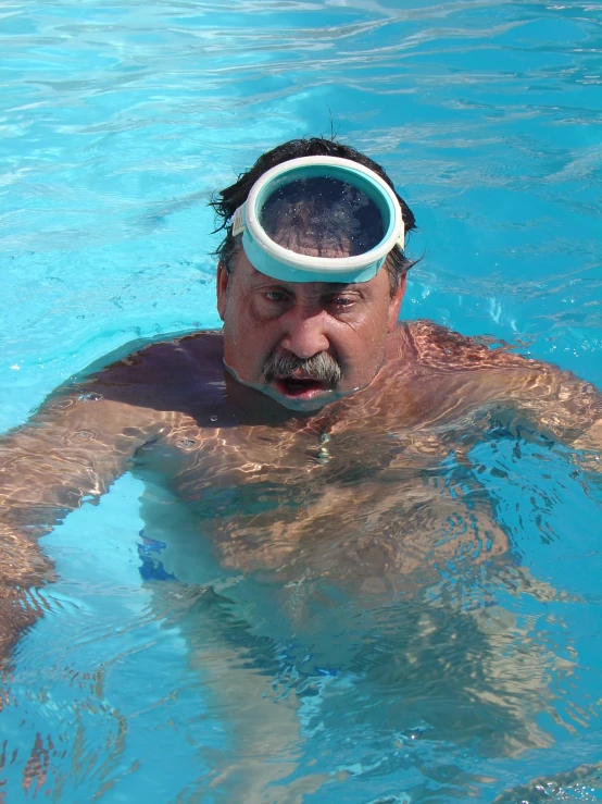 a man swimming in a blue pool wearing goggles