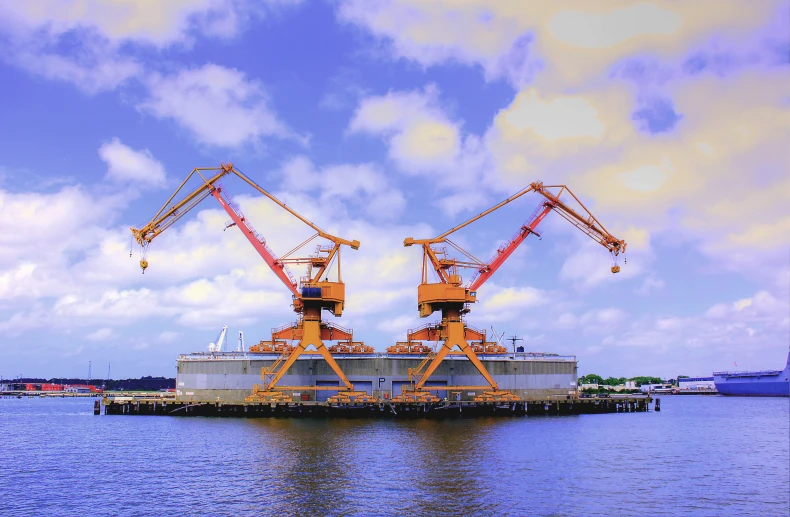 two cranes sit atop a ship in the water