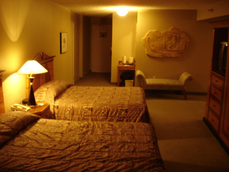 two beds are in a el room with lamps on and a couch