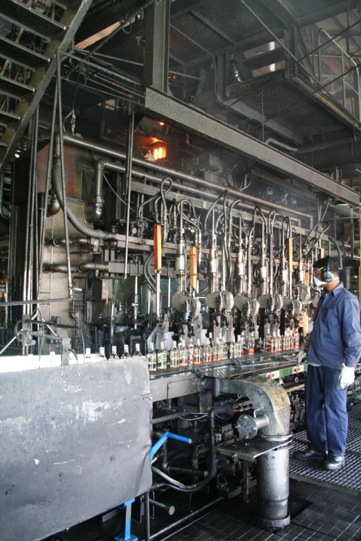an factory worker is operating a machine for filling bottles