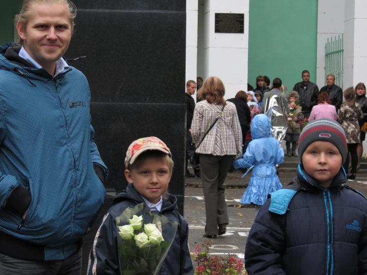 a man and two boys standing in front of people