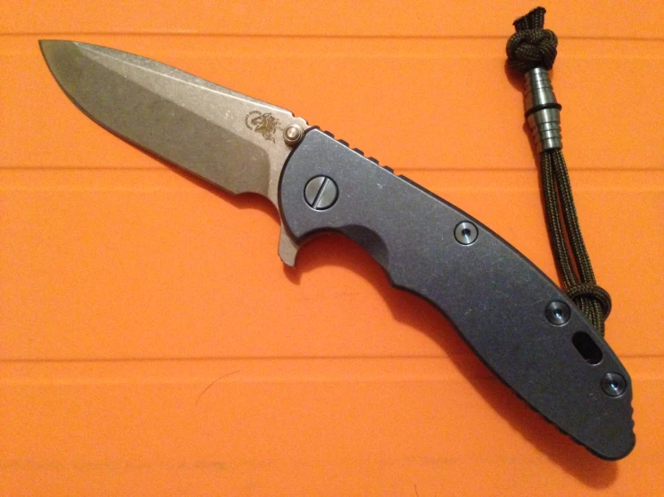 the large folding pocket knife sits on an orange background