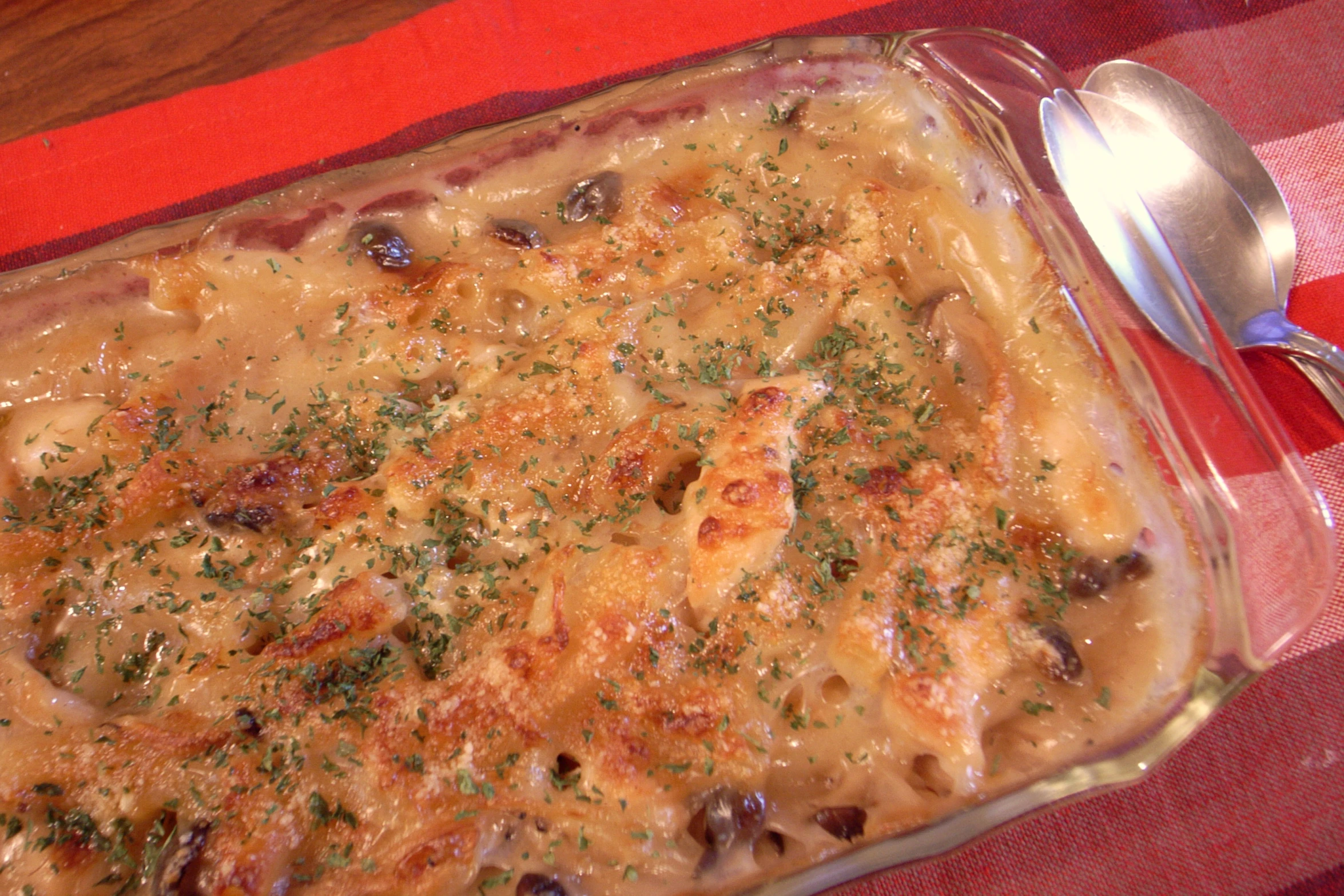 a large casserole dish with cheese, olives and bread