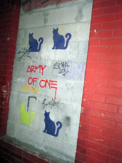 a red brick wall painted with stickers, with cats and words painted on it