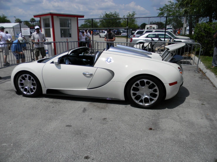 a white car parked next to a fence in the parking lot