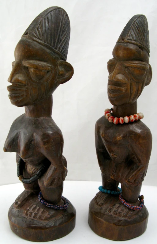 the two carved wooden figures are both wearing necklaces