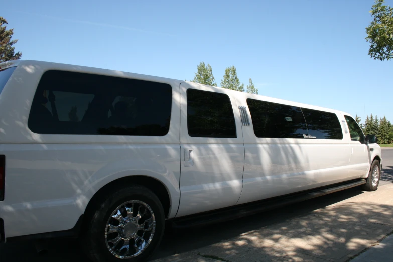 a white bus with some silver wheels parked on the side of the road