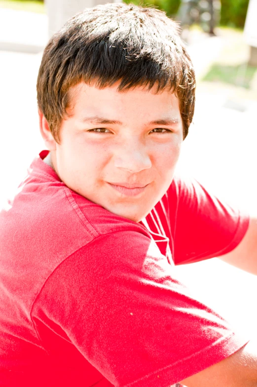 a boy sitting on the ground with his arms crossed