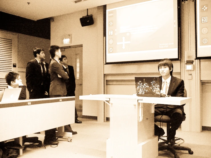 several men standing at podiums and sitting around a table