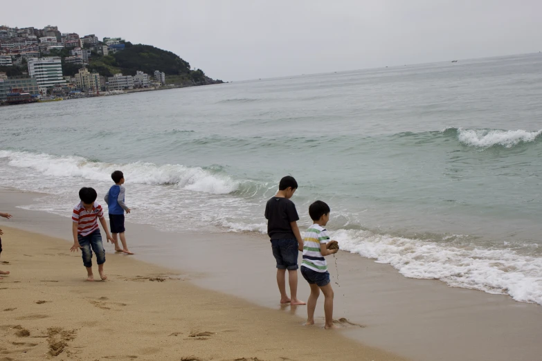 three people standing on the shore watching the ocean