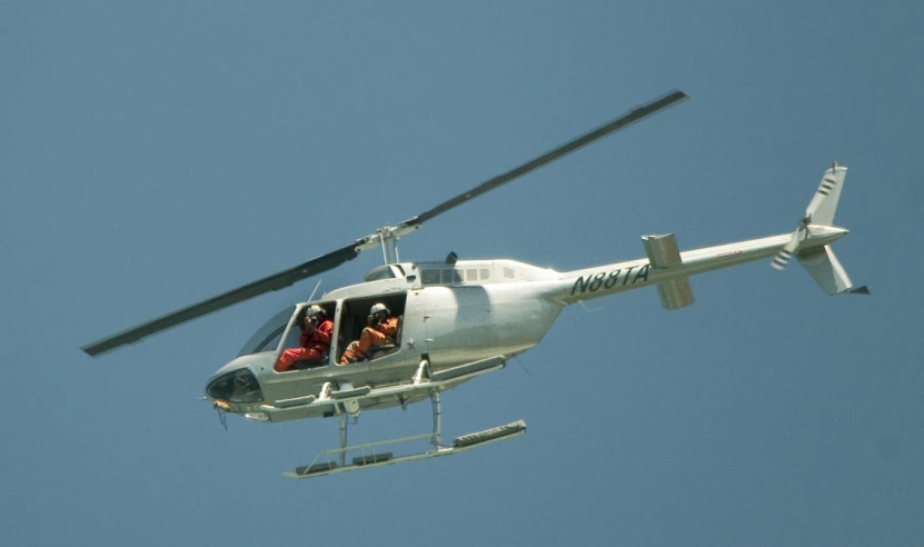 a helicopter flies overhead in the clear blue sky