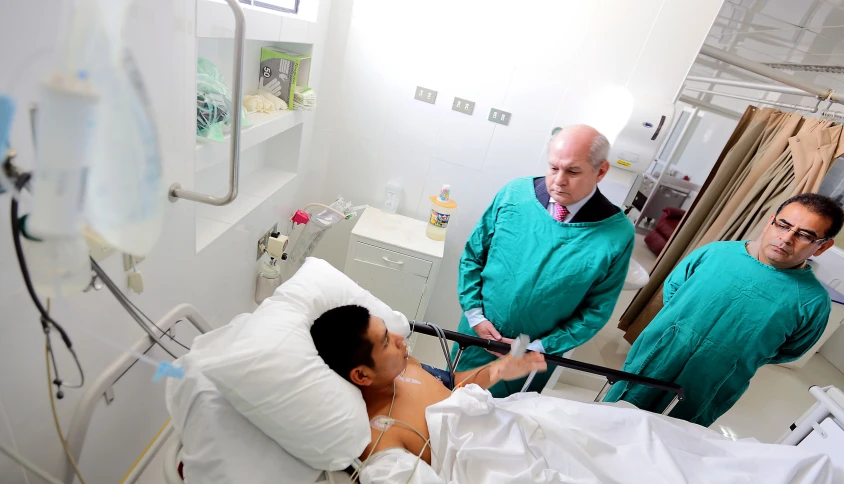 three people in green jackets in a hospital bed
