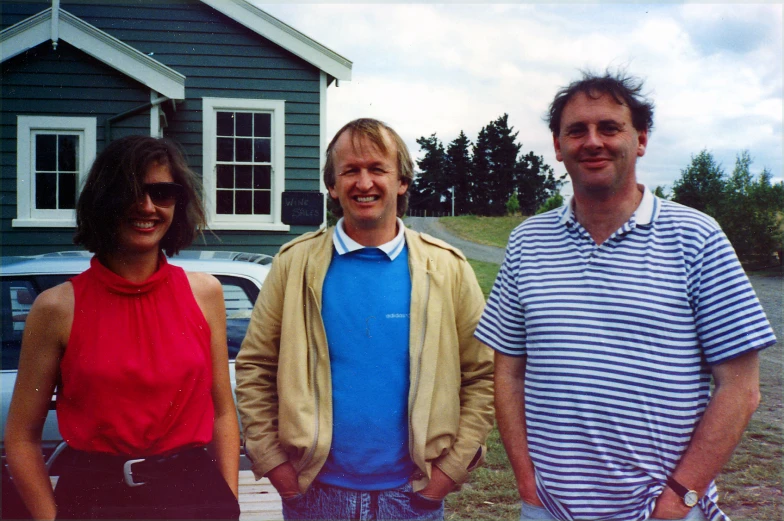 three people standing next to each other by a house