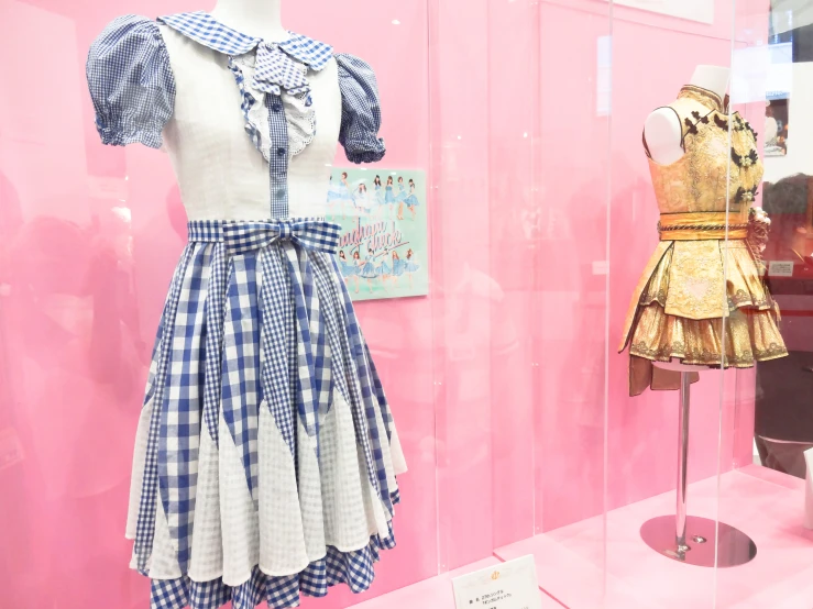 a display with mannequins, dresses and pink walls