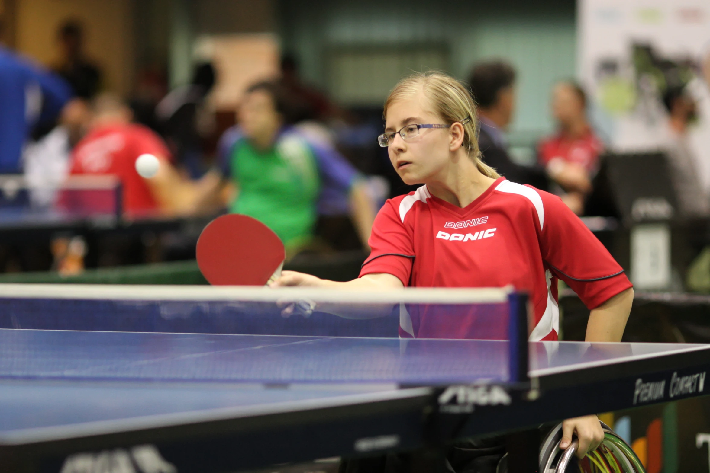 young woman in red shirt holding tennis racket with ball on it