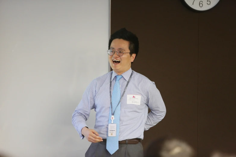 a man smiles while leaning against the wall wearing a tie