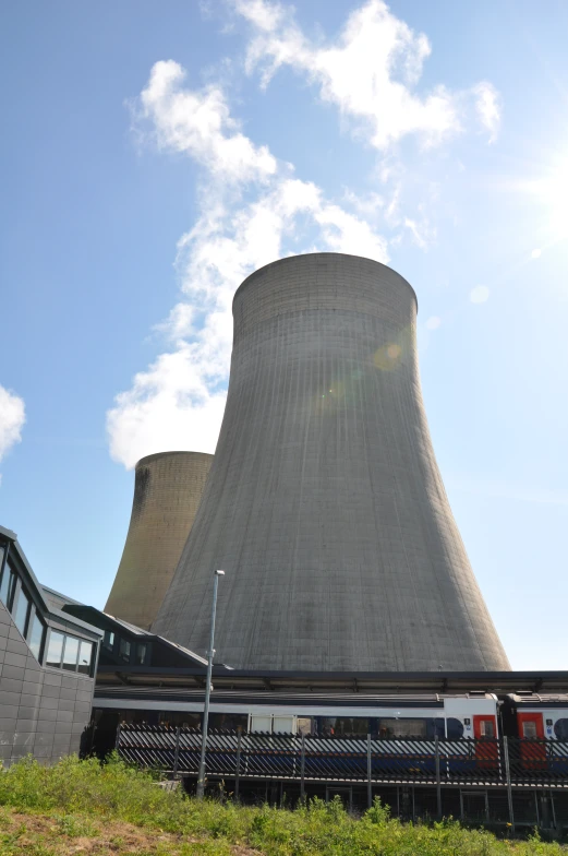 a tall cooling tower next to two buildings