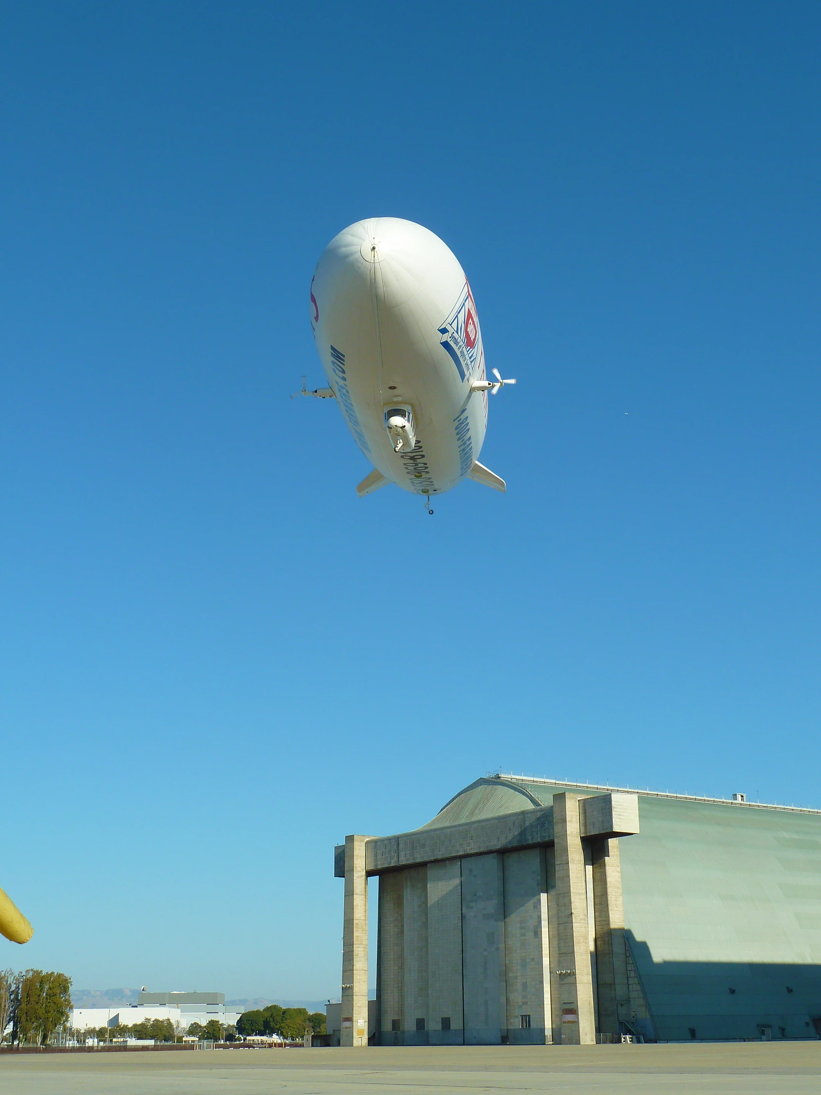 a large white air plane flying over a hangar