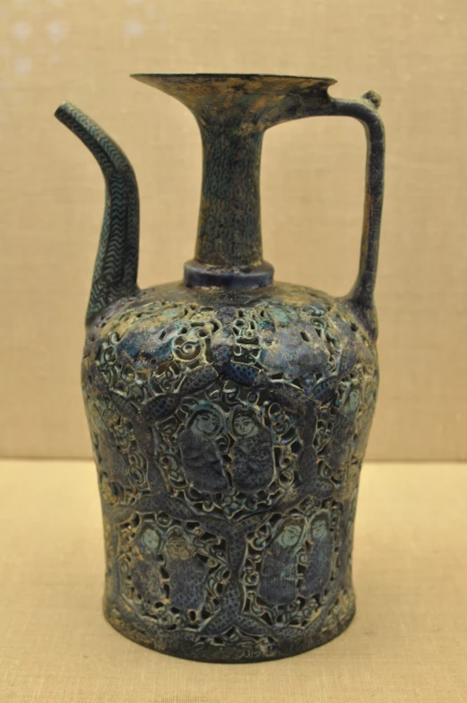 an antique vase with a curved handle that has many patterns