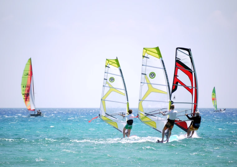 three windsurfers are sailing on the ocean