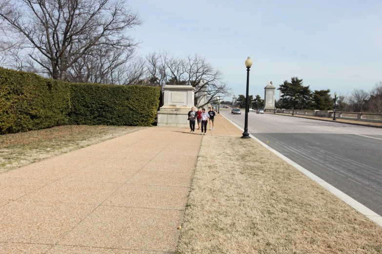 group of people walking up sidewalk near a lamppost