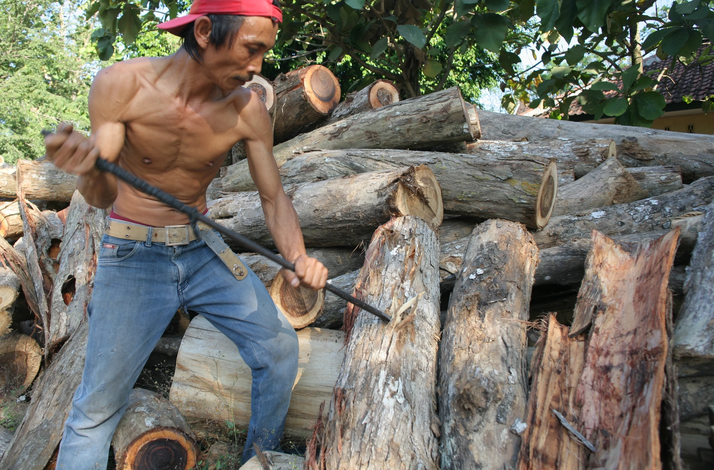 there is a man in a red hat and jeans chopping a log