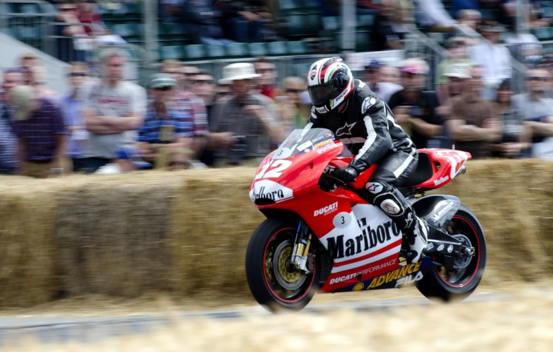 a motorcycle rider is turning a corner while people look on