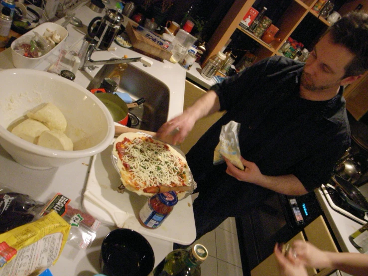 man preparing a pizza inside of a kitchen