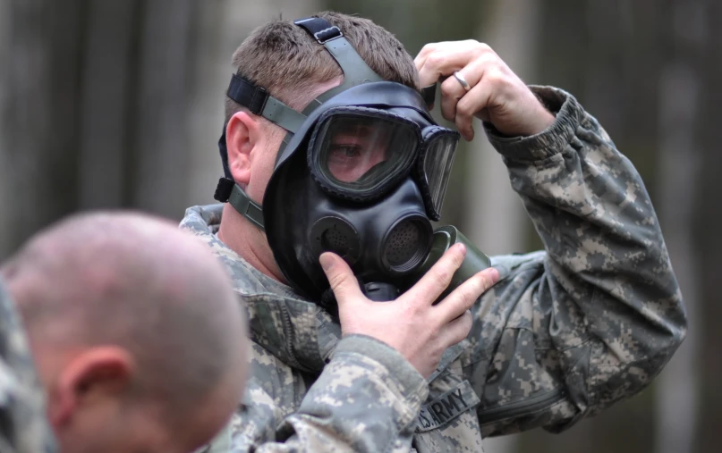 soldier holding on to a respirator mask while wearing a military uniform