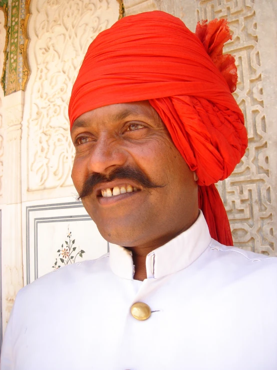 man in orange turban smiling for the camera