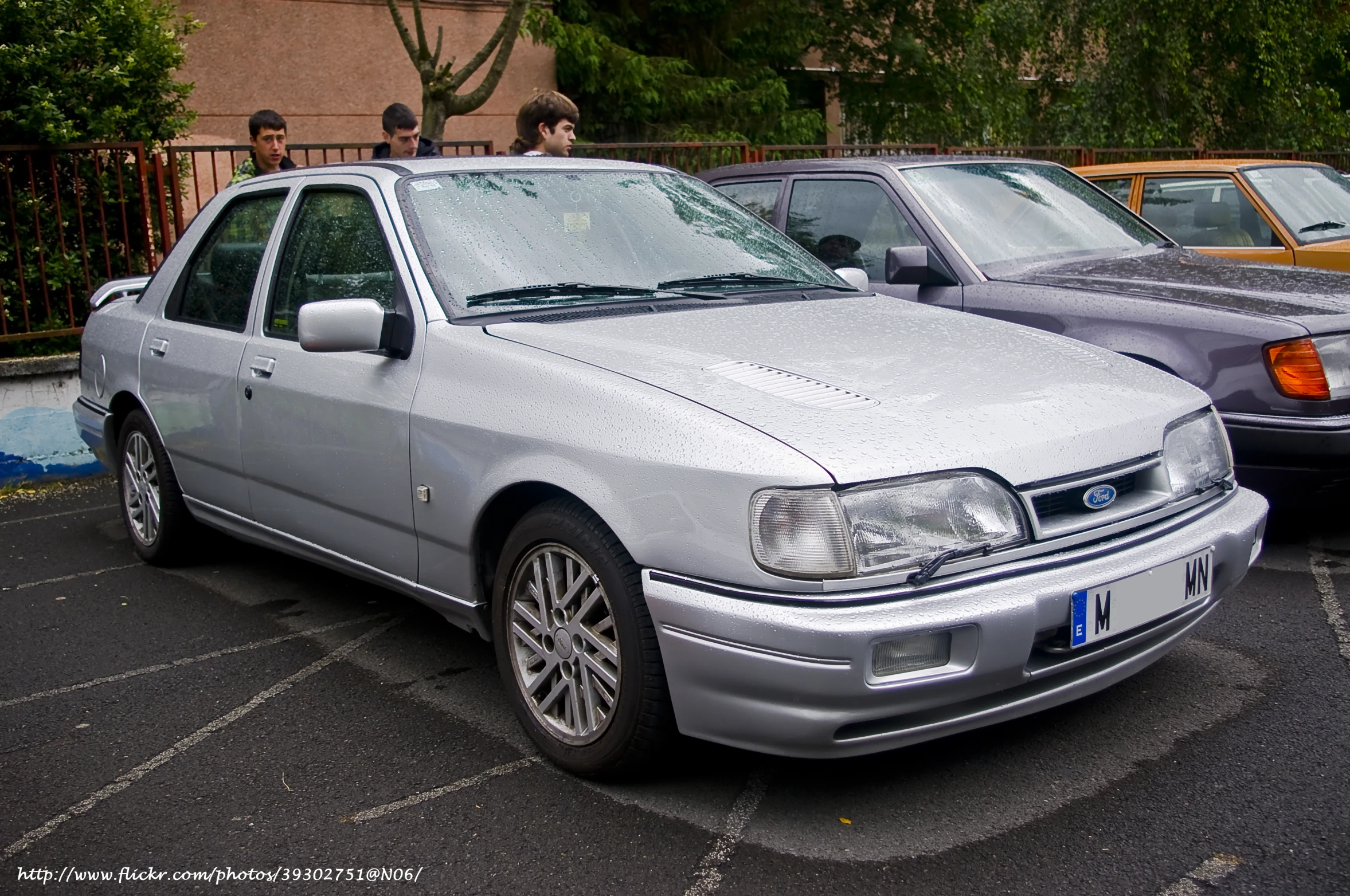 a silver four door car is parked on the parking lot with others